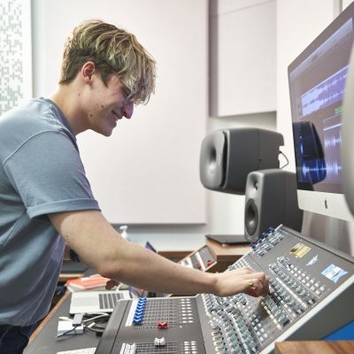 Electronic music student at a mixing desk in a studio